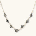 Adjustable cream cord necklace with white spotted stone beads featuring black speckles on neutral background
