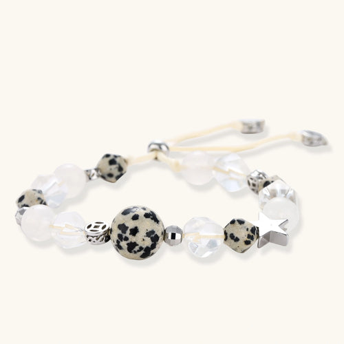Adjustable beaded bracelet with spotted dalmatian stones, clear quartz crystals, and silver star charm on white background.
