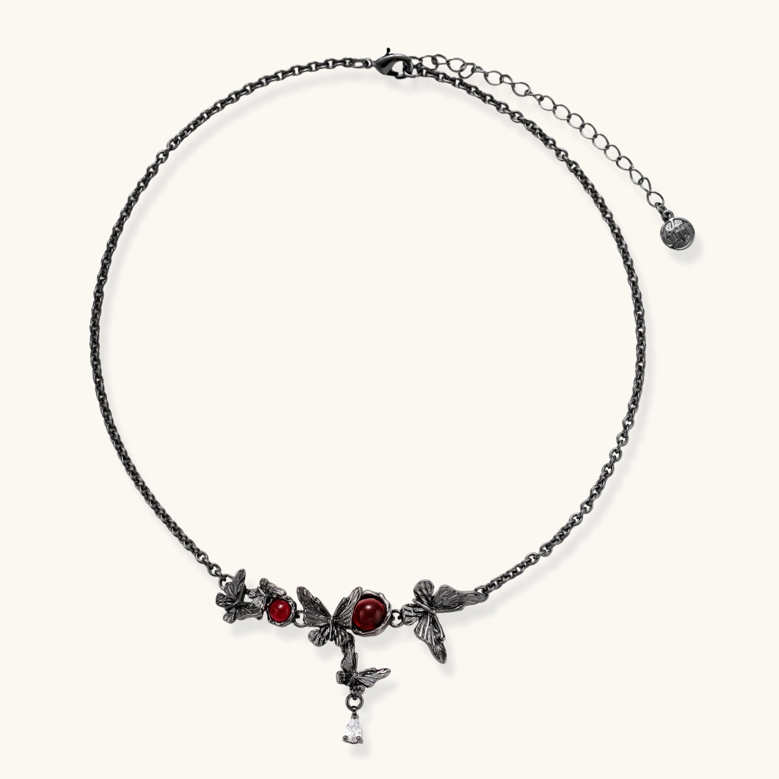 Dark oxidized metal necklace featuring red resin stones set in decorative leaf vine design with crystal drop pendant.